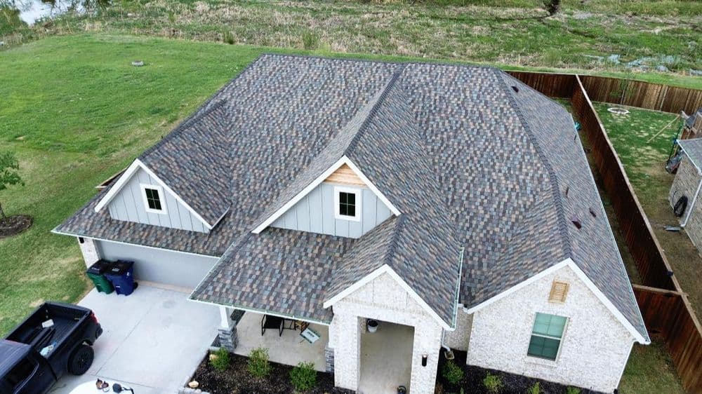 Aerial view of a modern house with a textured roof and manicured lawn.
